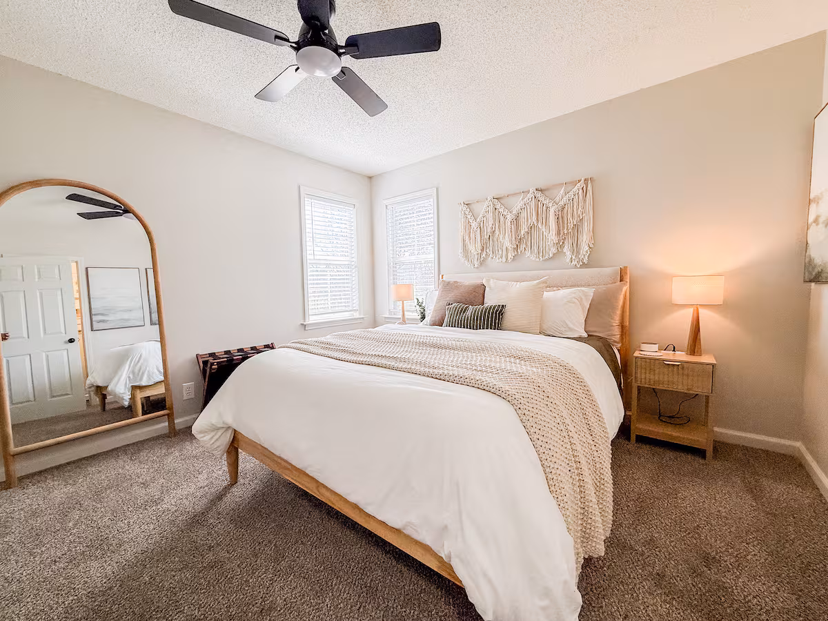 Guest bedroom with wood bed frame and arched mirror